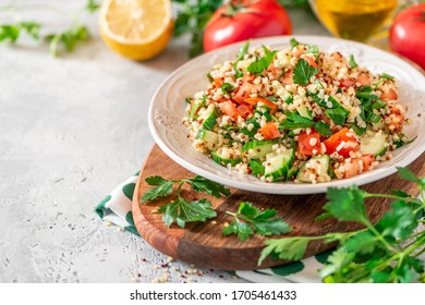 Tabbouleh salad - traditional Middle Eastern or Arabic cuisine. Levantine vegetarian salad with bulgur, quinoa, tomato, cucumber, parsley and lemon juice. Tabbouleh with bulgur closeup