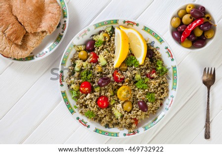 Tabbouleh, tabouleh salad with vege meatballs, pita bread and olives, a refreshing mediterranean salad made with mint, parsley and lemon, on white wooden table, rustic style