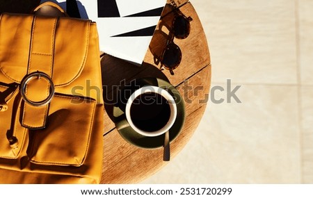 Table, above and bag with coffee by book for travel guide, information and cafe beverage in morning. Backpack, glasses and warm drink at restaurant for vacation, agenda and itinerary of holiday