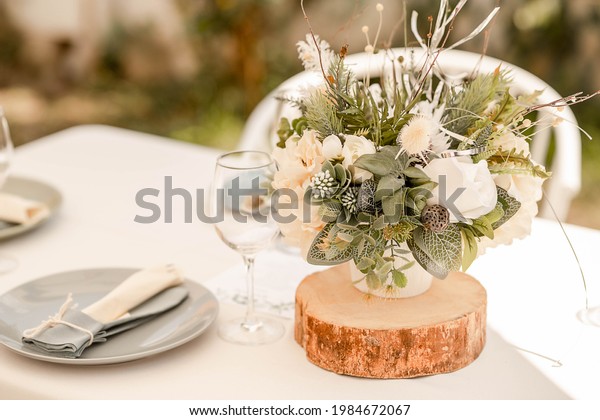 Table arrangement with natural rustic notes\
featuring herbal floral centerpieces, soft linen table cloth and\
pastel details, elegant setup for guests at a wedding reception,\
restaurant or at a party