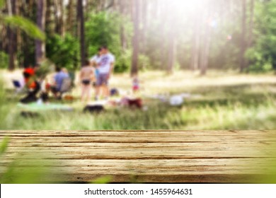 Table Background With Wooden Table Top. Forest And Gardens View In Distance. Time For Picnic And Barbecue With Family. Happy Family Moments.