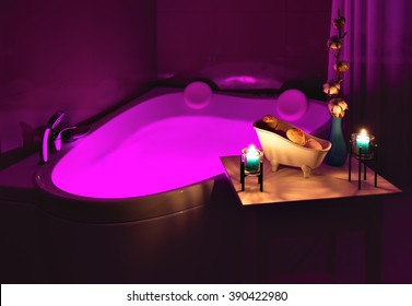 Table with bath products and candles stands near the spa