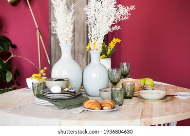 table in the boho style with pineapple candles plant decoration with a set of dishes, vases with plants, glass, fruits and food. Horizontal photo