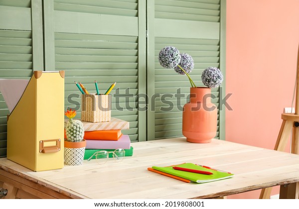 Table with books\
and vase near folding\
screen
