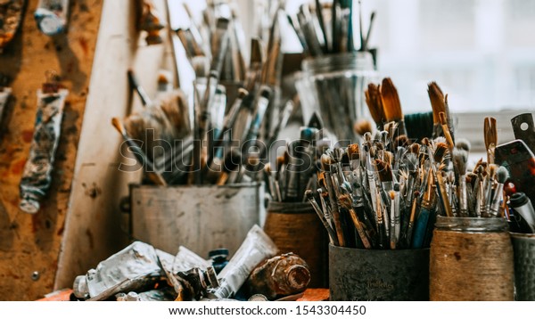 Table with brushes and tools in an art\
workshop. Background.