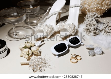 A table with a bunch of items including a pair of white shoes, a pair of sunglasses, and a bouquet of flowers