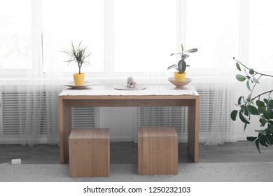 table with chairs. on the table flowers. brown table. by the window. interior. wooden table
