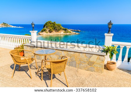 Table with chairs on a terrace with view of beautiful Kokkari bay, Samos island, Greece