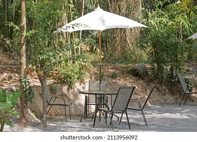 Table And Chairs Under A Sun Umbrella At An Outdoor Cafe In A Jungle Setting. No People.