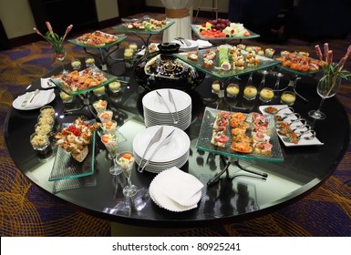 Table with cold snacks and tableware on luxury stand-up party