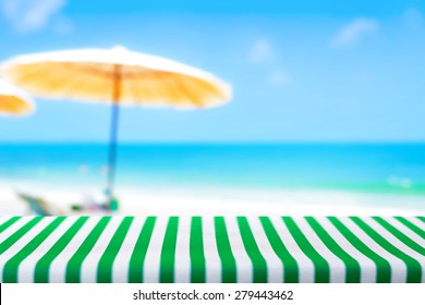 Table covered with striped tablecloth on blurred beach background - picnic and holiday concepts