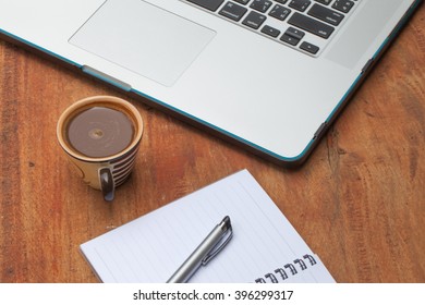 At the table with a cup of coffee. Notebook, pen and notebook computers.