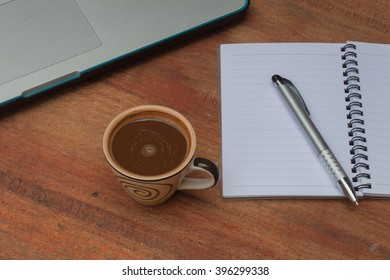 At the table with a cup of coffee. Notebook, pen and notebook computers.