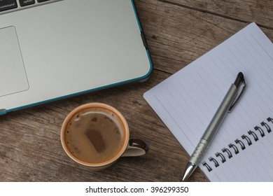 At the table with a cup of coffee. Notebook, pen and notebook computers.
