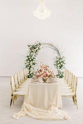 Table Decorated For A Wedding Celebration. Bouquets Of Pink, White And Peach Flowers, Vintage Decor. White Bright Room, An Arch Of Rose Flowers