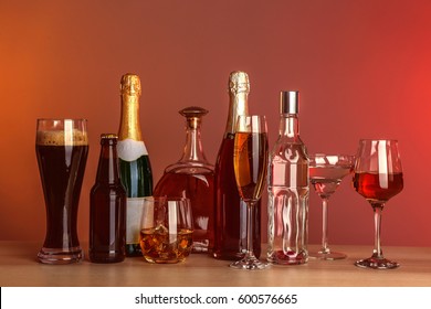 Table With Different Bottles Of Wine And Spirits On Color Background