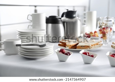 Table with different delicious snacks and dishware indoors. Coffee break