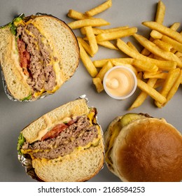 table with double cheeseburger and hamburger cut in half, french fries and sauce top view - Powered by Shutterstock