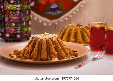 A table with eastern dessert kunafa or konafa - Famous Ramadan Arabian sweets with chocolate and 2 glasses of tea and Ramadan lantern in the background