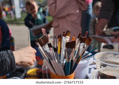 Table with face painting kit, featuring a close-up of a cup filled with brushes.