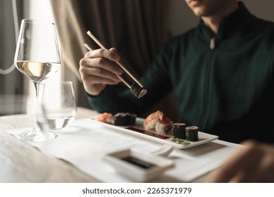 Table filled with friends, enjoying plates of sushi rolls, sashimi, and sake, in a relaxed and casual atmosphere. woman savoring every bite of a healthy delicious sushi roll, in trendy sushi bar