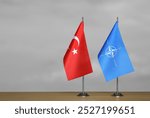 Table flags of Turkey and NATO on grey blurred background