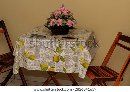 A table with a flower arrangement and two cell phones on it.
