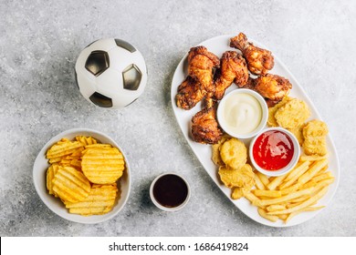 Table Fof Tasty Snacks For Beer Prepared For Watching Sports On TV. Chicken. Chicken Wings, Chicken Nuggets, French Fries, Chips, Various Sauces And Lemonade. Light Gray Background. Top View. Flat Lay