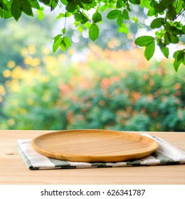 Table For Food Background, Empty Round Wooden Plate, Tray And Napkin On Wood Counter, Shelf Over Blur Green Tree Park, Garden In Spring Summer Nature Background, Banner, Backdrop, Template, Wallpaper