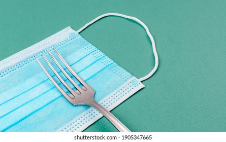 Table Fork On Medical Mask. The Concept Of The Entrance To The Restaurant And Dining Room In Mask. Masked Food