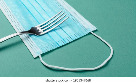 Table Fork On Medical Mask. The Concept Of The Entrance To The Restaurant And Dining Room In Mask. Masked Food