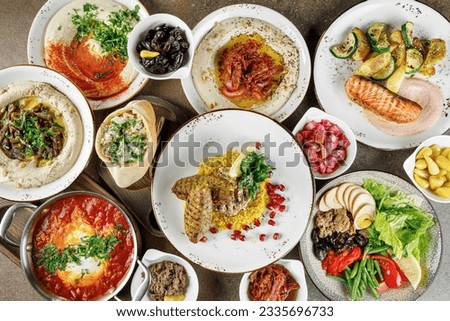 A table full of various dishes 
arabic cuisine: hummus, shakshuka, falafel, tortillas, fish, vegetables