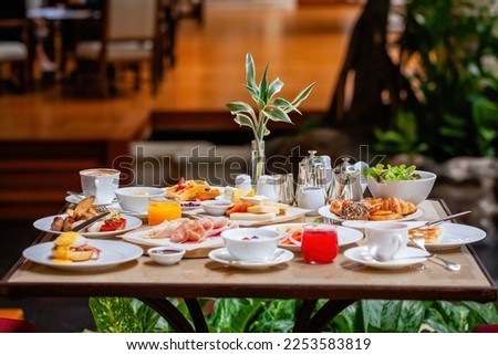 Table full of various fresh food in luxury modern restaurant in hotel. Delicious dishes, including fruits, pastries, and cooked meals on table. Restaurant setting. Breakfast or morning meal