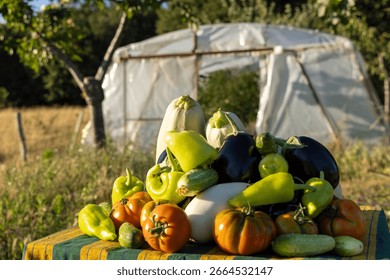 A table full of vegetables including tomatoes, peppers, and cucumbers. The vegetables are piled on top of each other, creating a colorful and inviting display. The scene suggests a sense of abundance