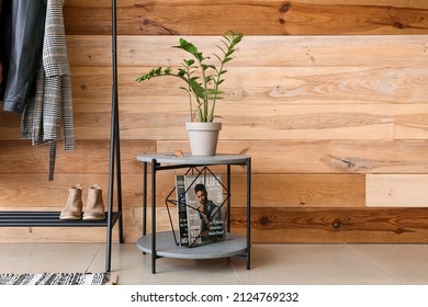 Table With Houseplant And Magazine Stand Near Wooden Wall