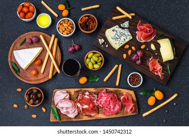 Table of Italian antipasti starters and appetizers with cold meats and cheese delicatessen platter, wine, bread sticks, olives, nuts, and cherry tomatoes