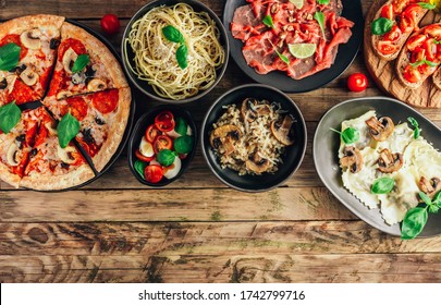 Table of italian meals on plates Pizza, pasta, ravioli, carpaccio, mushroom risotto, caprese salad and tomato bruschetta on rustic wooden background. Top view. Flat lay with place for text - Shutterstock ID 1742799716