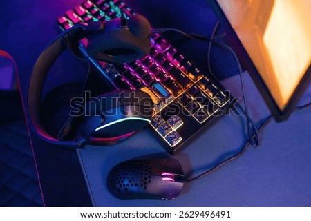 Table with keyboard. Gaming computer is in the dark room with neon lighting.