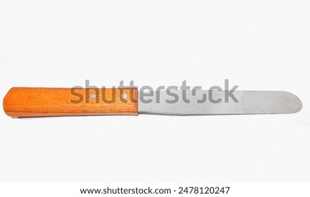 Table knife with rounded point used to serve and spread butter. Cooking utensils cake spatula palette or knife pastry kitchen spatula with wooden handle for cakes on table on white background close-up