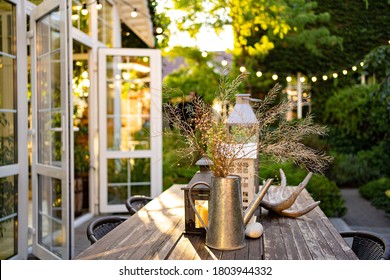 table for lunch outside in the garden in the courtyard with the lights of a country house at sunset. landscape design in the cottage. - Shutterstock ID 1803944332