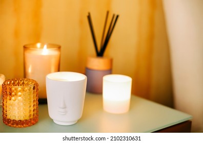 Table with many burning lighting scented candles and aromatic incense sticks in spa massage salon or yoga studio, selective focus. Meditation place in home interior. Aromatherapy concept