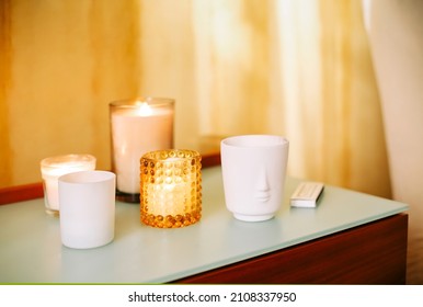 Table with many burning lighting scented candles and aromatic incense sticks in spa massage salon or yoga studio, selective focus. Meditation place in home interior. Aromatherapy concept