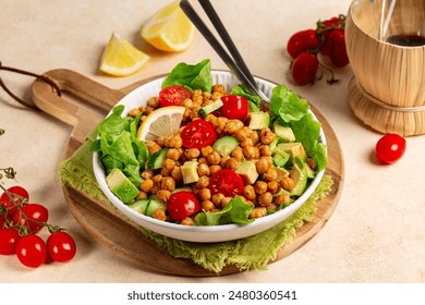 Table with mediterranean chickpea salad. Chickpea and paprika baked beans, lettuce, tomatoes, avocado, cucumber, lemon and olive oil dressing. Healthy high protein vegan meal.