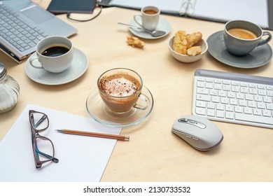 Table At A Meeting With Laptop, Keyboard, Folder And Papers And Various Coffee Cups, Light Wood, Nobody, Selected Focus, Narrow Depth Of Field