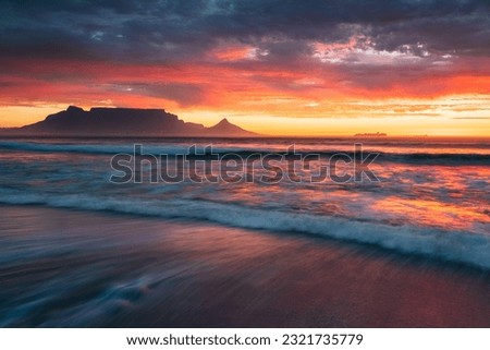 Table Mountain at sunset from Blouberg Beach with waves rolling in
