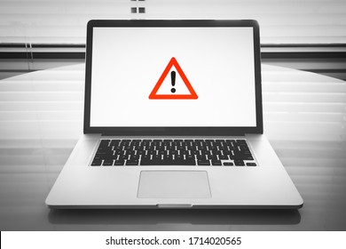 Table With a Notebook Computer  Screen That Displays a Symbol which May Mean One of The Following Messages: Caution, Attention, Warning, Error, Halt - Shutterstock ID 1714020565