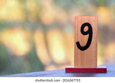 Table Number Sign Decor. Nine Number Printing On Wood Board With Blurred Backgroun. Focos On Foreground