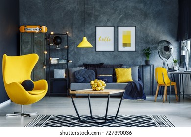 Table On Black And White Carpet In Hygge Style Living Room With Designer Yellow Chair