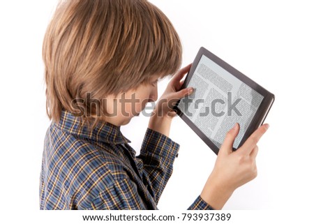 Table pc and other gadgets can cause eye problems - Young boy reading an article on a tablet device holding it too close to his eyes. Isolated on white.
