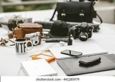 Table With Photography Gear, Camera Bags, Laptop, External Laptop Power, External Rugged Hard Drive And Drawing Tablet.